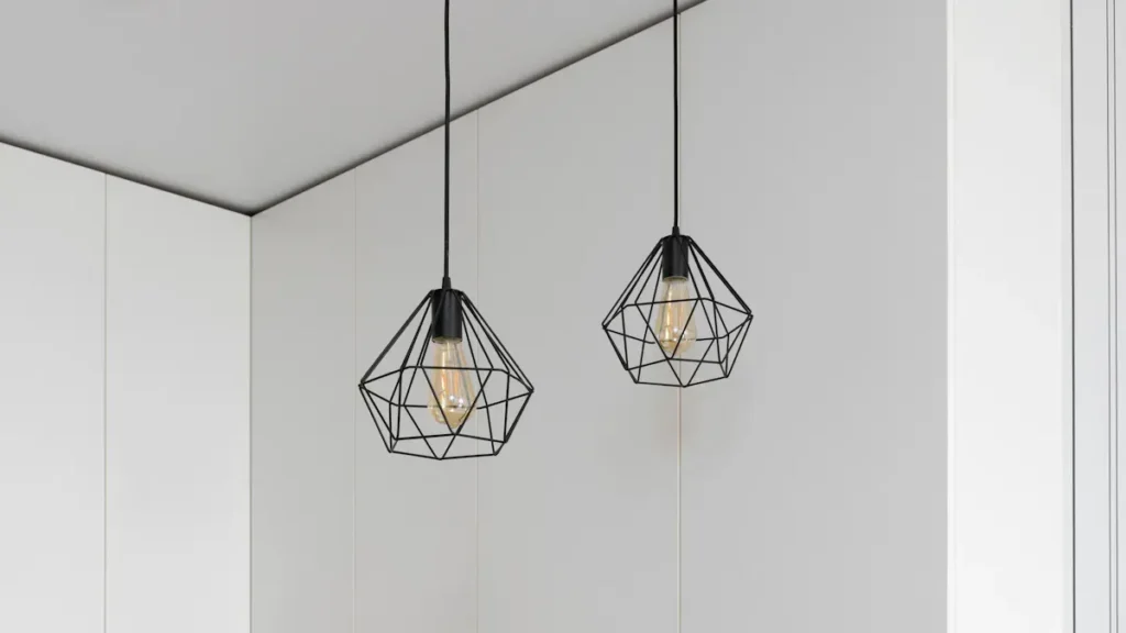 Two geometric pendant lights against a white wall