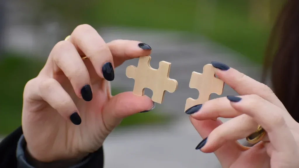 Hands bringing two puzzle pieces together