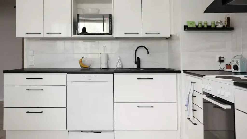 White kitchen cabinets with black countertops and handles