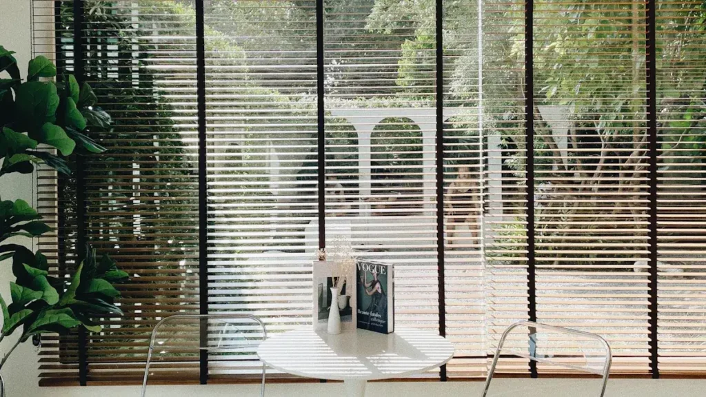 Window blinds filtering daylight beside indoor plants