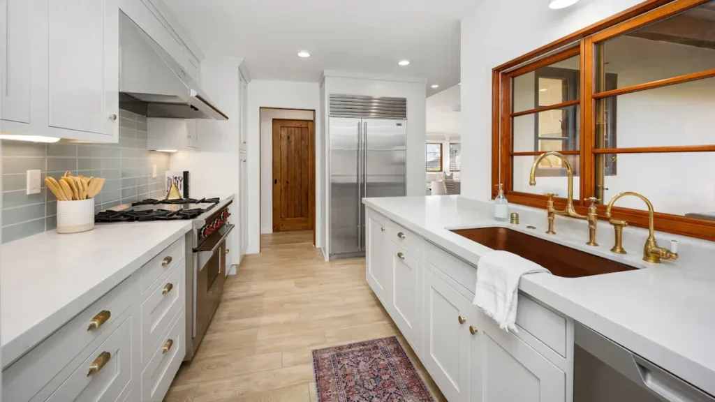 White kitchen cabinetry with long countertops and wood framed windows