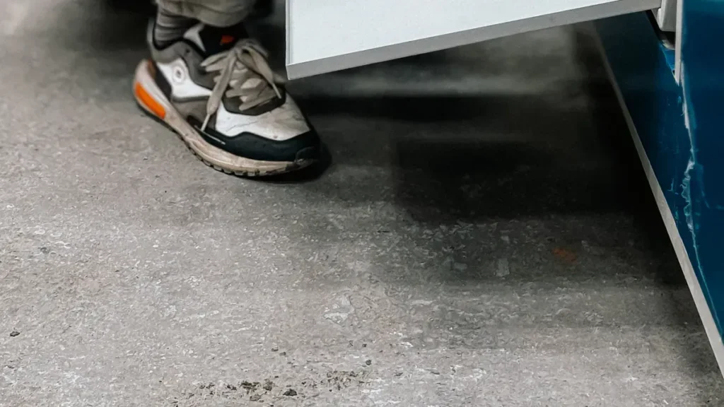 Person standing beside a metal cabinet or machine base