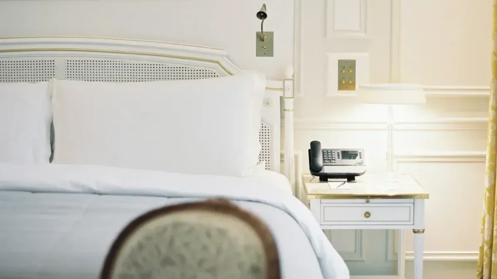 Hotel bedroom with white linens and a bedside table