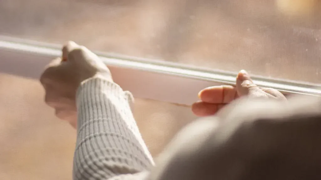 Person inspecting the lower edge of a window frame