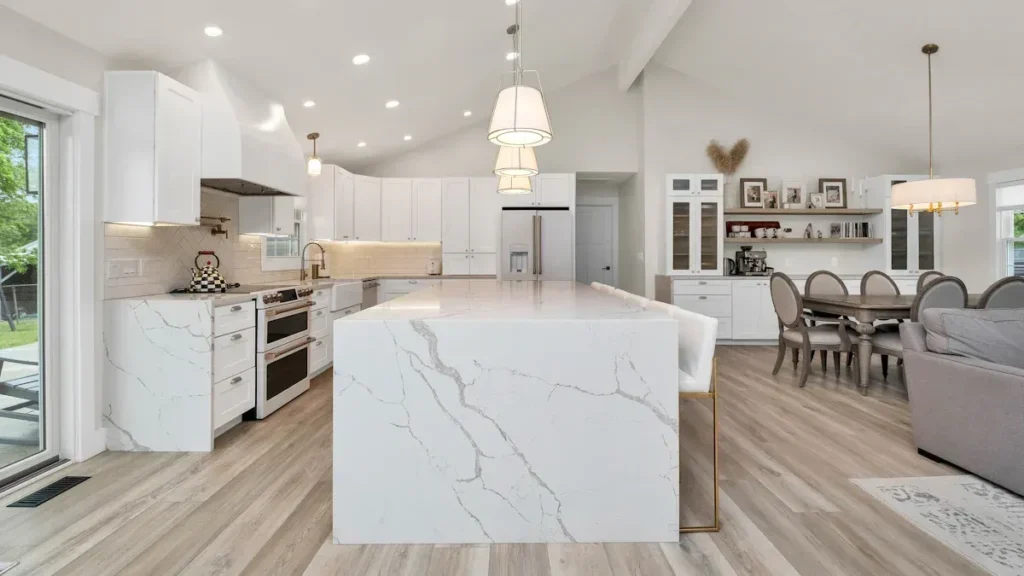 Open plan kitchen with white cabinets and a marble look island