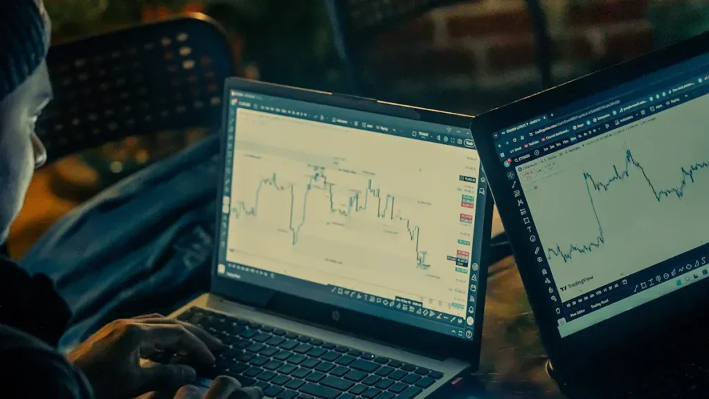 Two laptop screens displaying financial charts