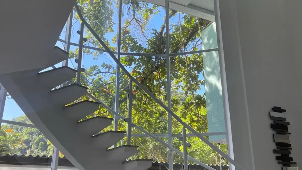 Open riser metal stairs beside a tall glazed wall