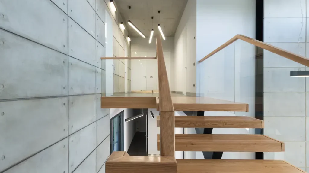 Floating wooden stair treads beside a concrete wall